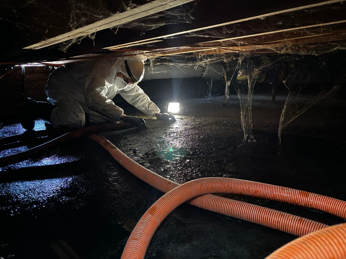 Technician working in a flooded crawl space