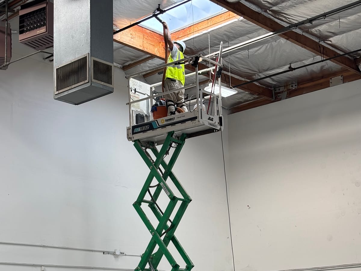 Technician repairing ceiling storm damage from a lift
